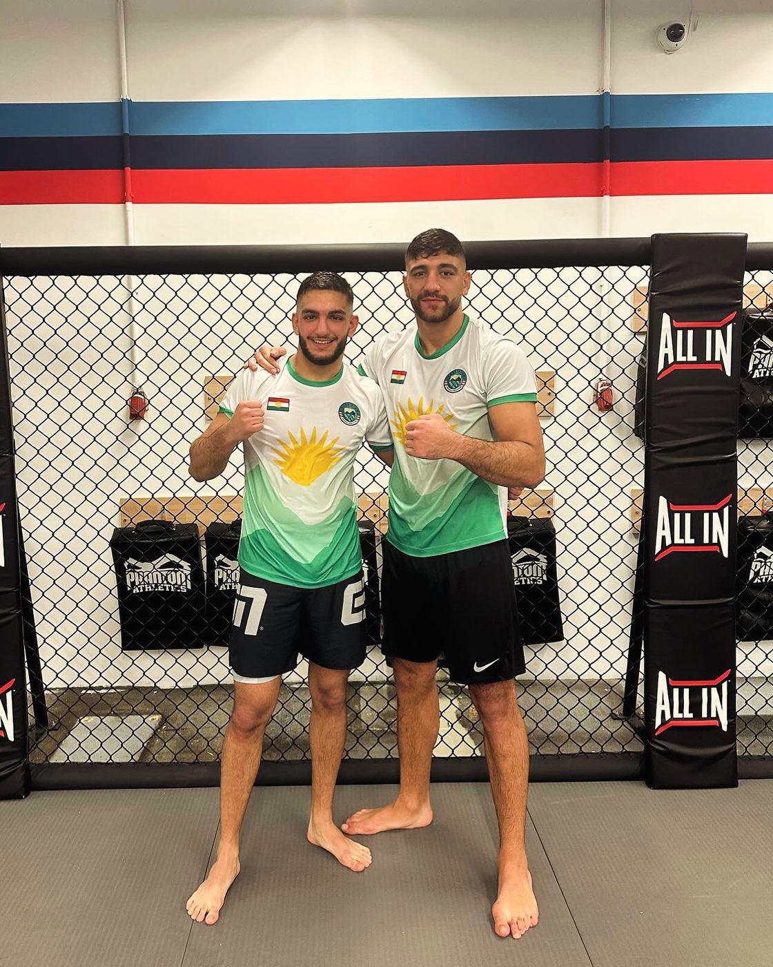 Deux combattants kurdes de MMA en maillots Çiyayê Kurdî devant la cage