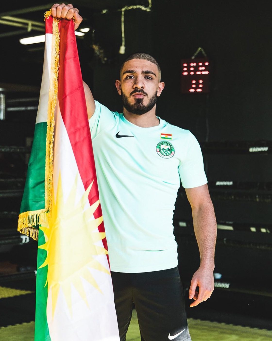 Combattant kurde de MMA tenant le drapeau du Kurdistan dans la salle d'entraînement