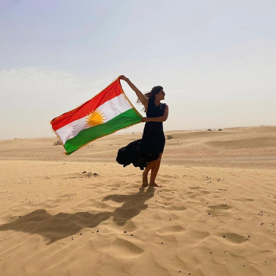 Femme kurde portant le drapeau du Kurdistan dans le désert